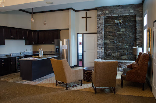 A cozy lounge area featuring modern armchairs and a sleek kitchen with a stone wall accent.