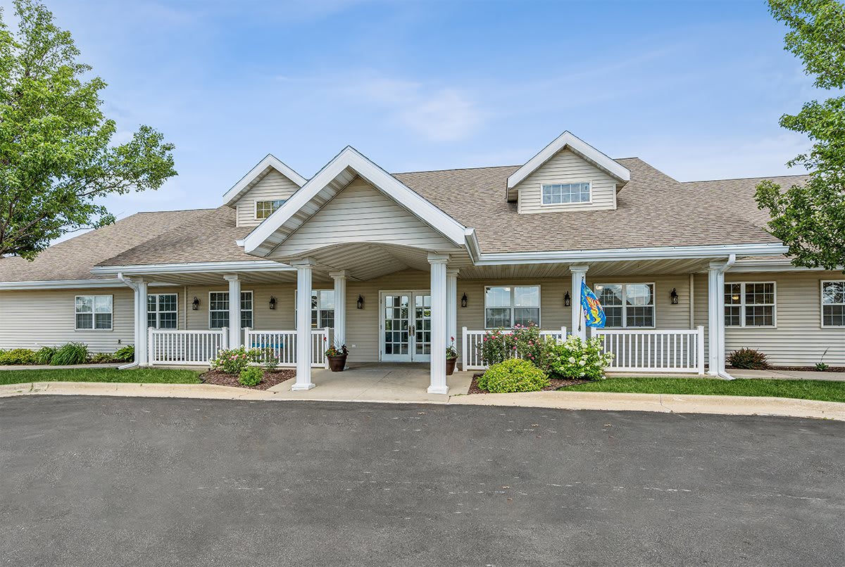 A large house with a front porch and neatly landscaped surroundings under a clear blue sky.
