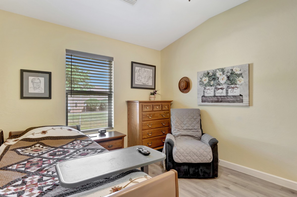 A cozy room with a hospital bed, recliner chair, and a dresser against the wall.