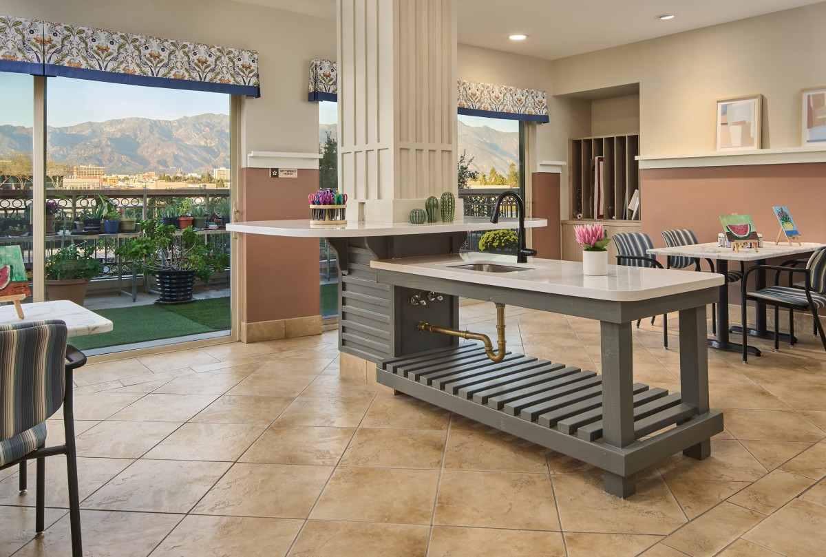 A modern kitchen interior with large windows and a central countertop.