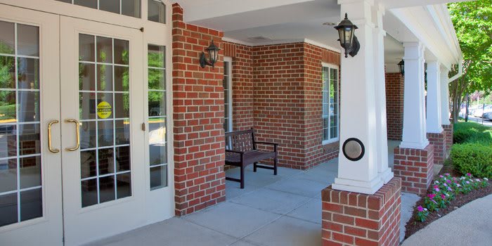 A cozy porch with brick walls, a bench, and decorative lanterns.
