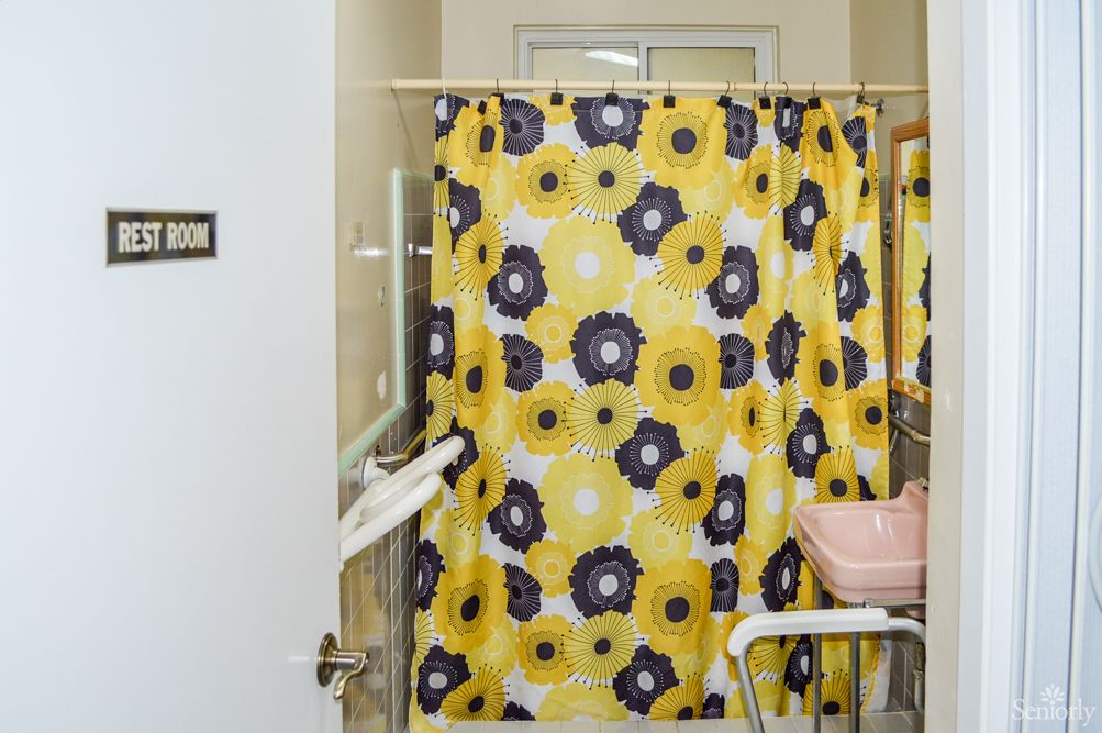 A bathroom with a vibrant yellow shower curtain featuring a floral pattern.