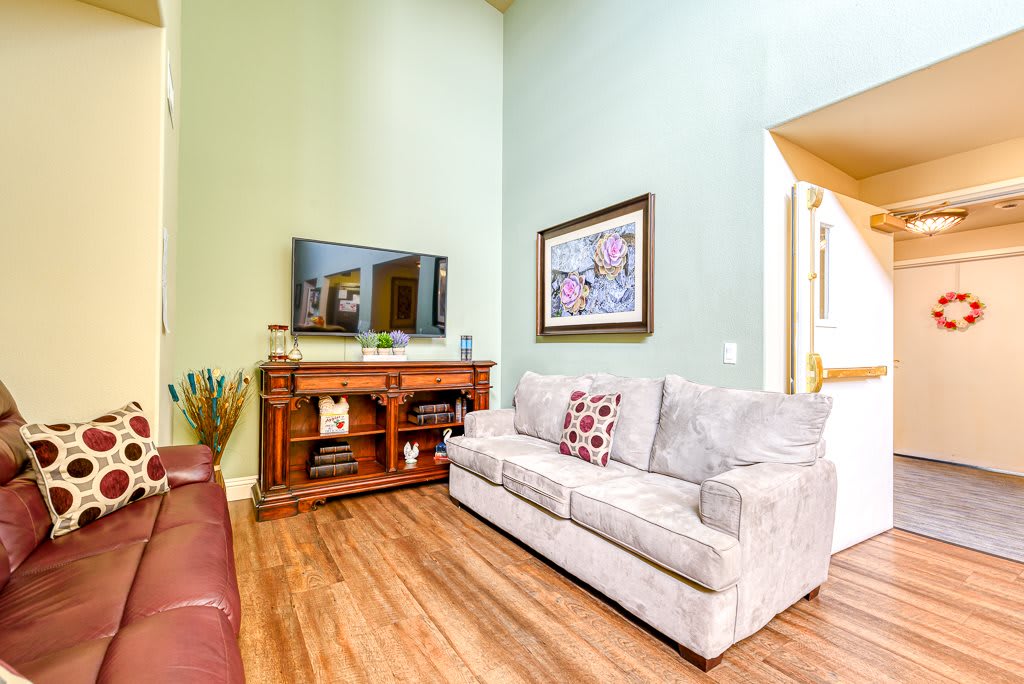 A cozy living room with a comfortable sofa, wooden flooring, and a television setup.