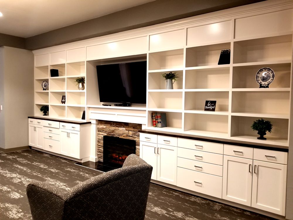 A modern living room with built-in shelves, a TV, and a fireplace.