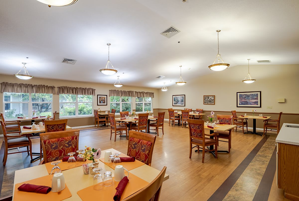 A well-lit dining room with neatly arranged tables and chairs, decorated with framed pictures on the walls.
