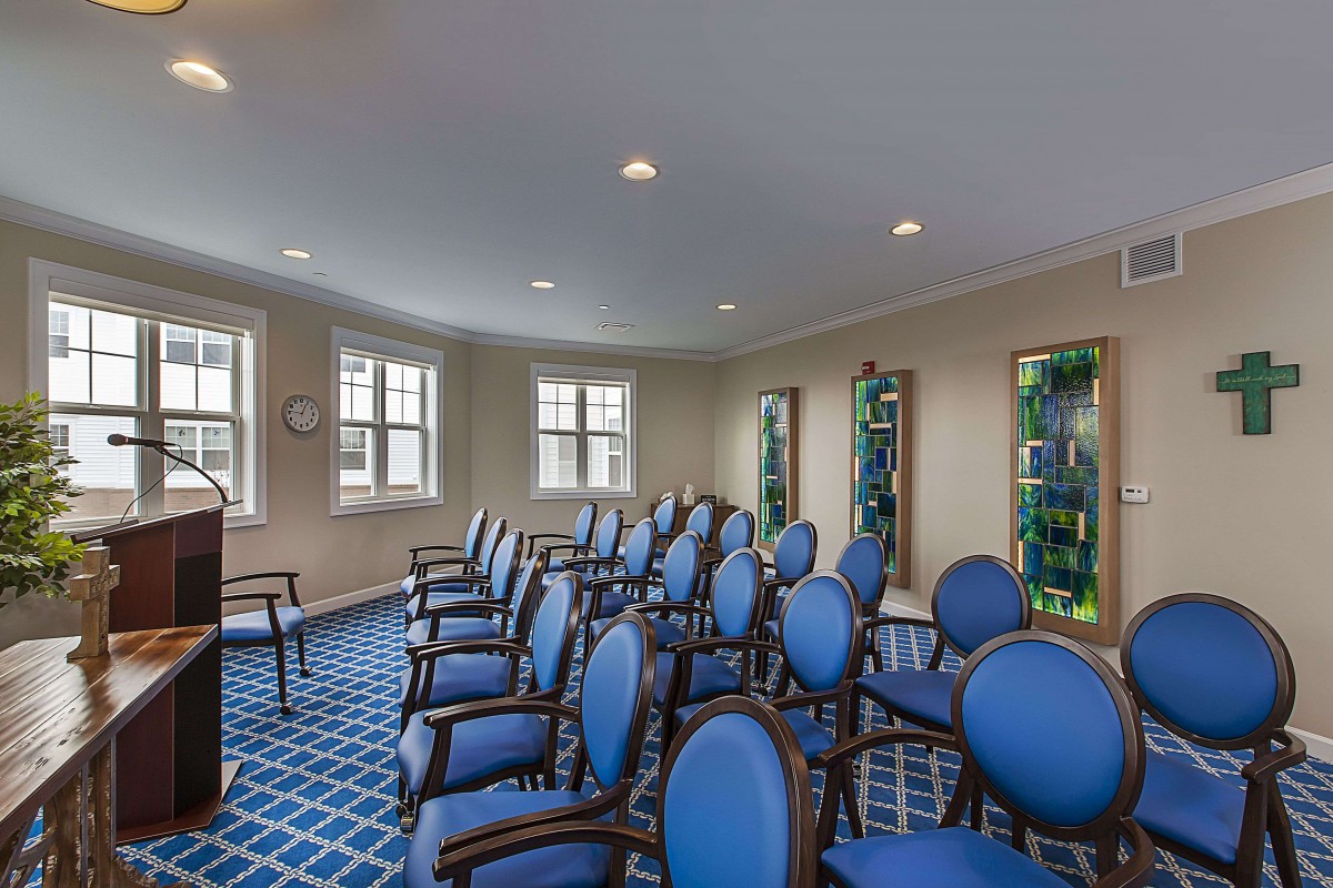 A small meeting room set up with rows of blue chairs facing the front.