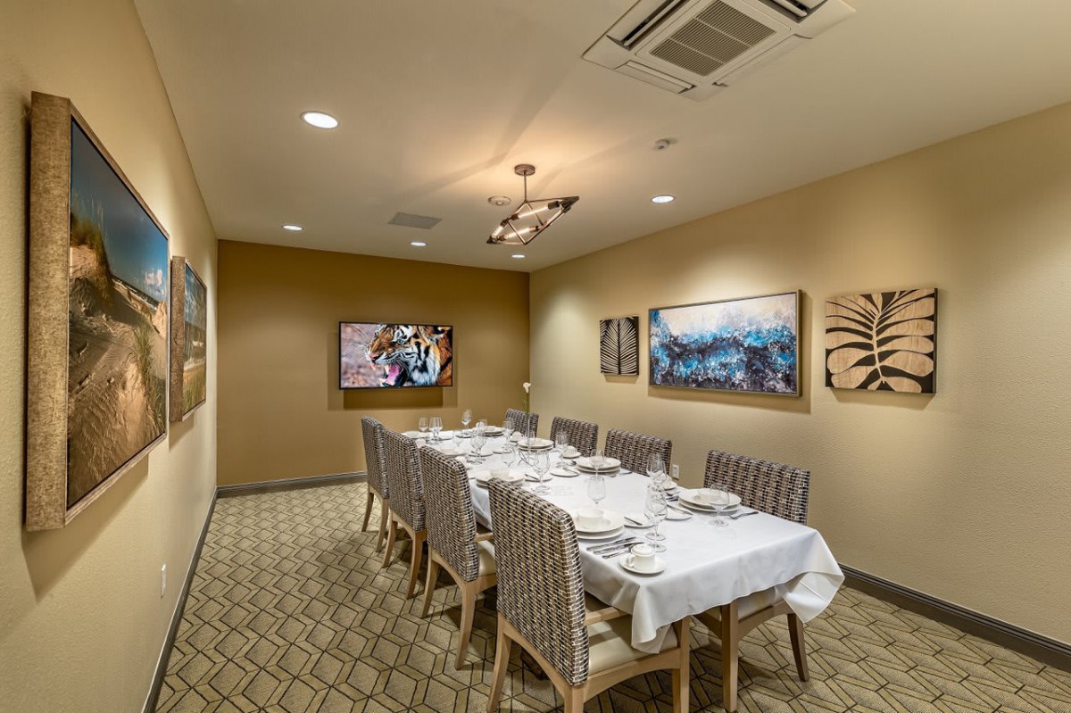 An elegantly set dining table in a private room adorned with artwork on the walls.