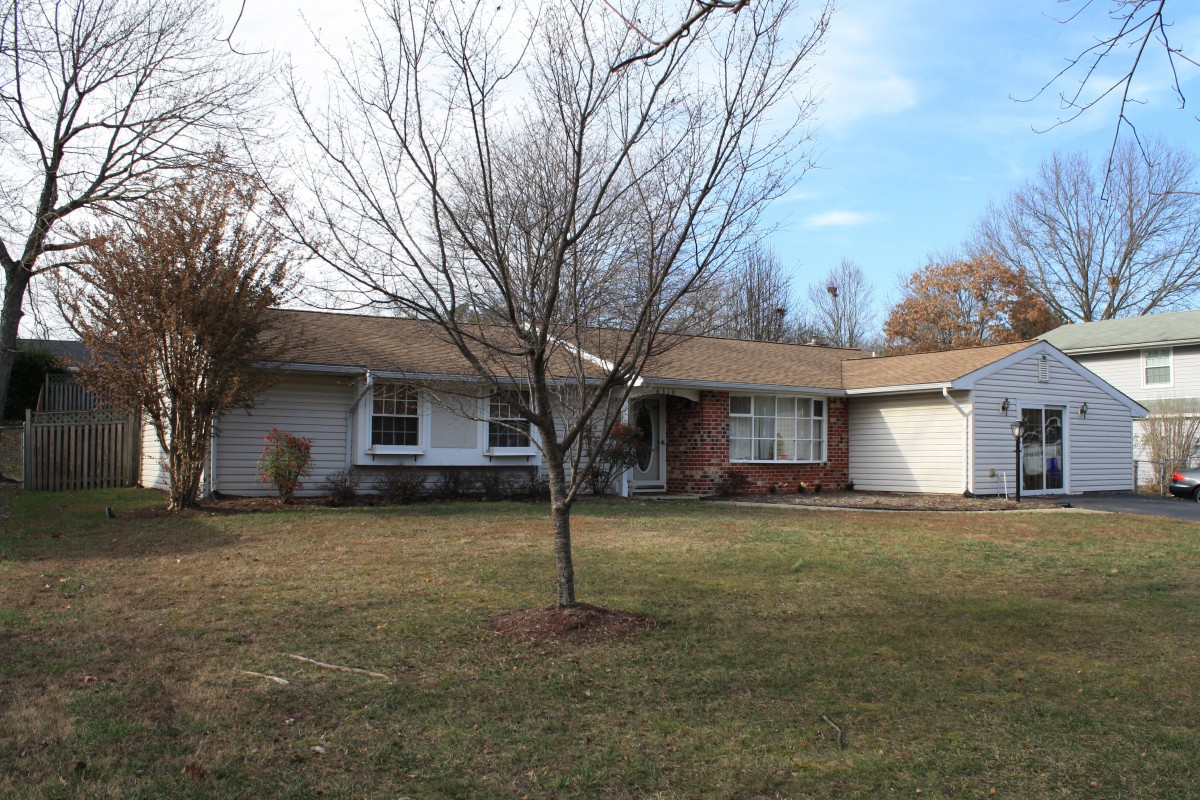A suburban ranch-style house with a tree in the front yard.
