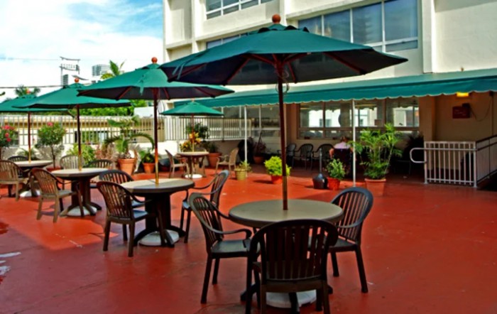 A sunny outdoor patio with tables, chairs, and umbrellas.
