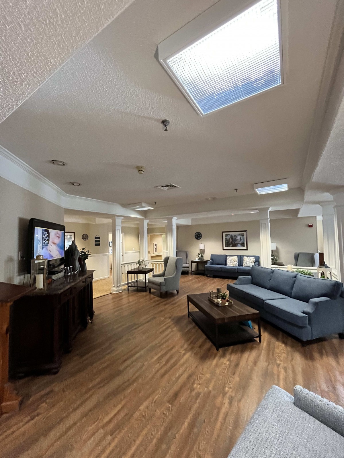 A spacious living room with modern furniture, including several couches and a television, set on a wooden floor.