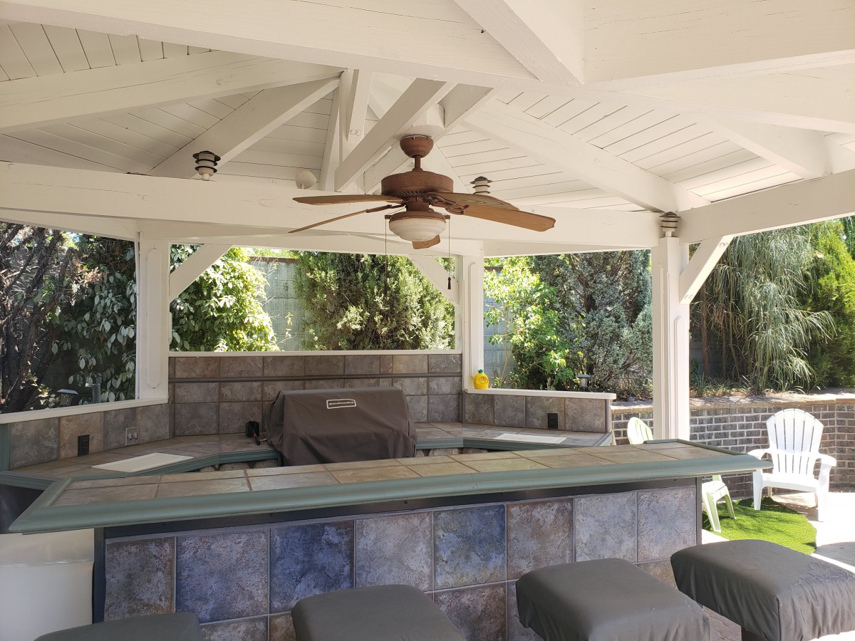 A cozy outdoor patio bar area with seating and a ceiling fan.