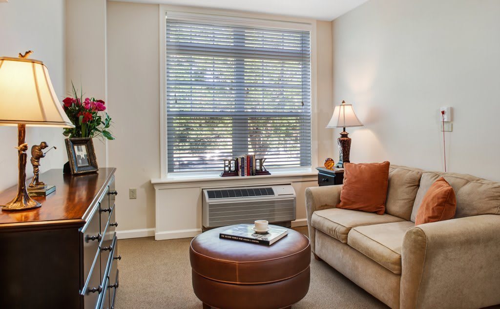 A cozy living room with a sofa, lamp, and coffee table near a window.