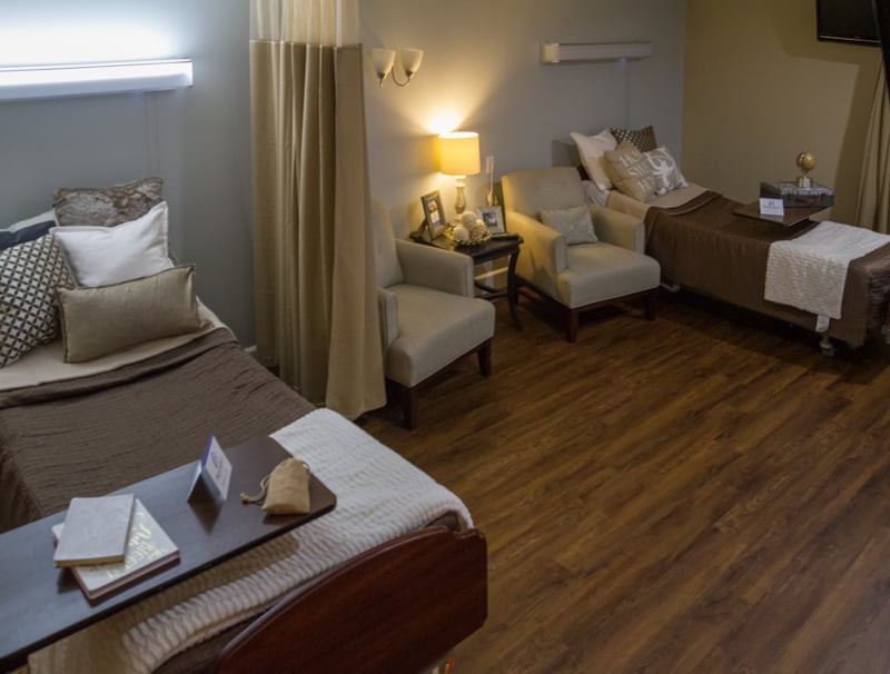 A cozy hospital room with two beds and comfortable seating.