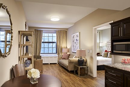 A cozy living room with modern furnishings and a view into a bedroom.