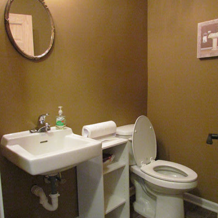 A simple bathroom interior featuring a sink, toilet, and mirror.