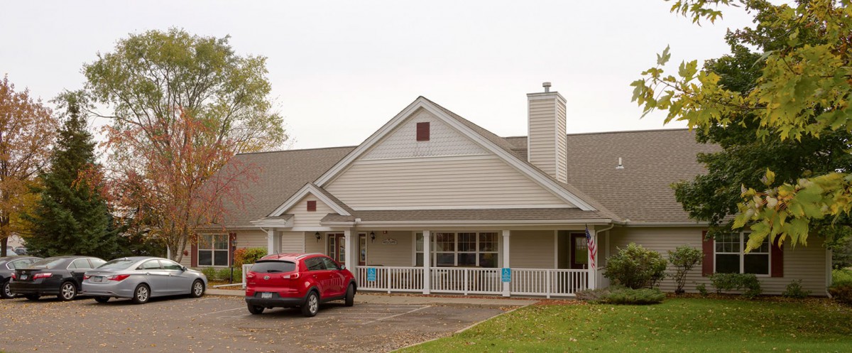 A residential house with a red car parked in the driveway.