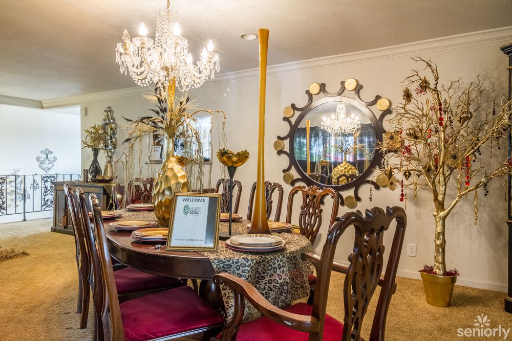 A beautifully decorated dining room with an elegant chandelier and ornate mirror.