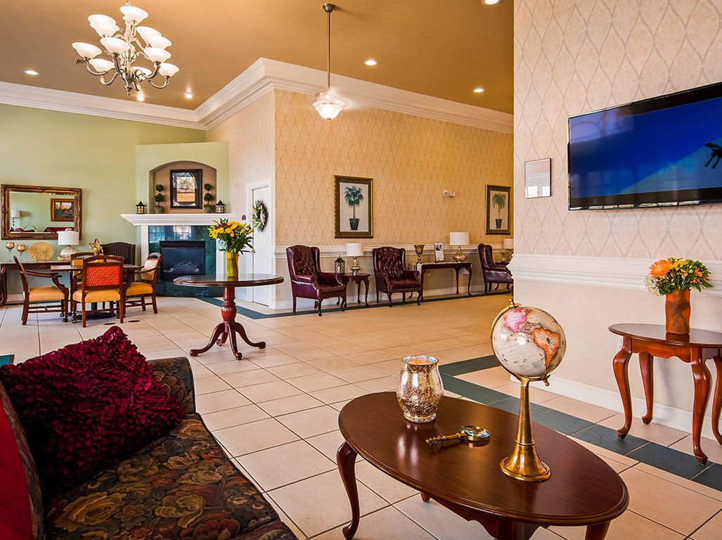 A well-decorated hotel lobby featuring comfortable seating, elegant lighting, and a mounted television.