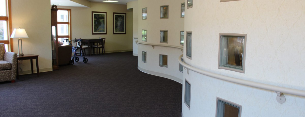 A modern interior hallway with curved walls and small windows.
