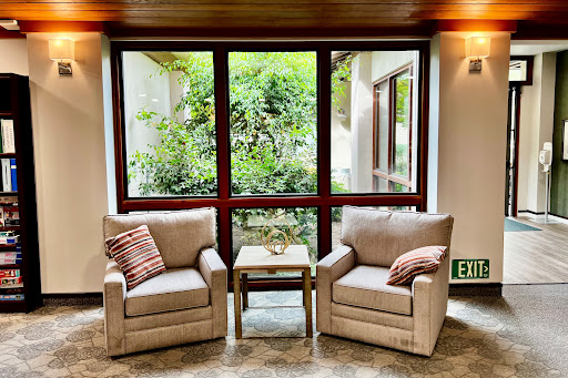 A cozy seating area with two chairs and a view of lush greenery outside.