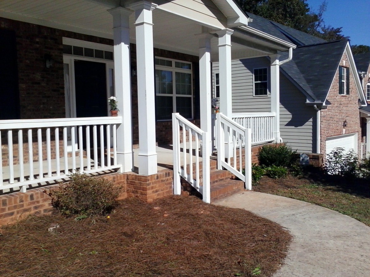 A house with a front porch featuring white railings and steps.