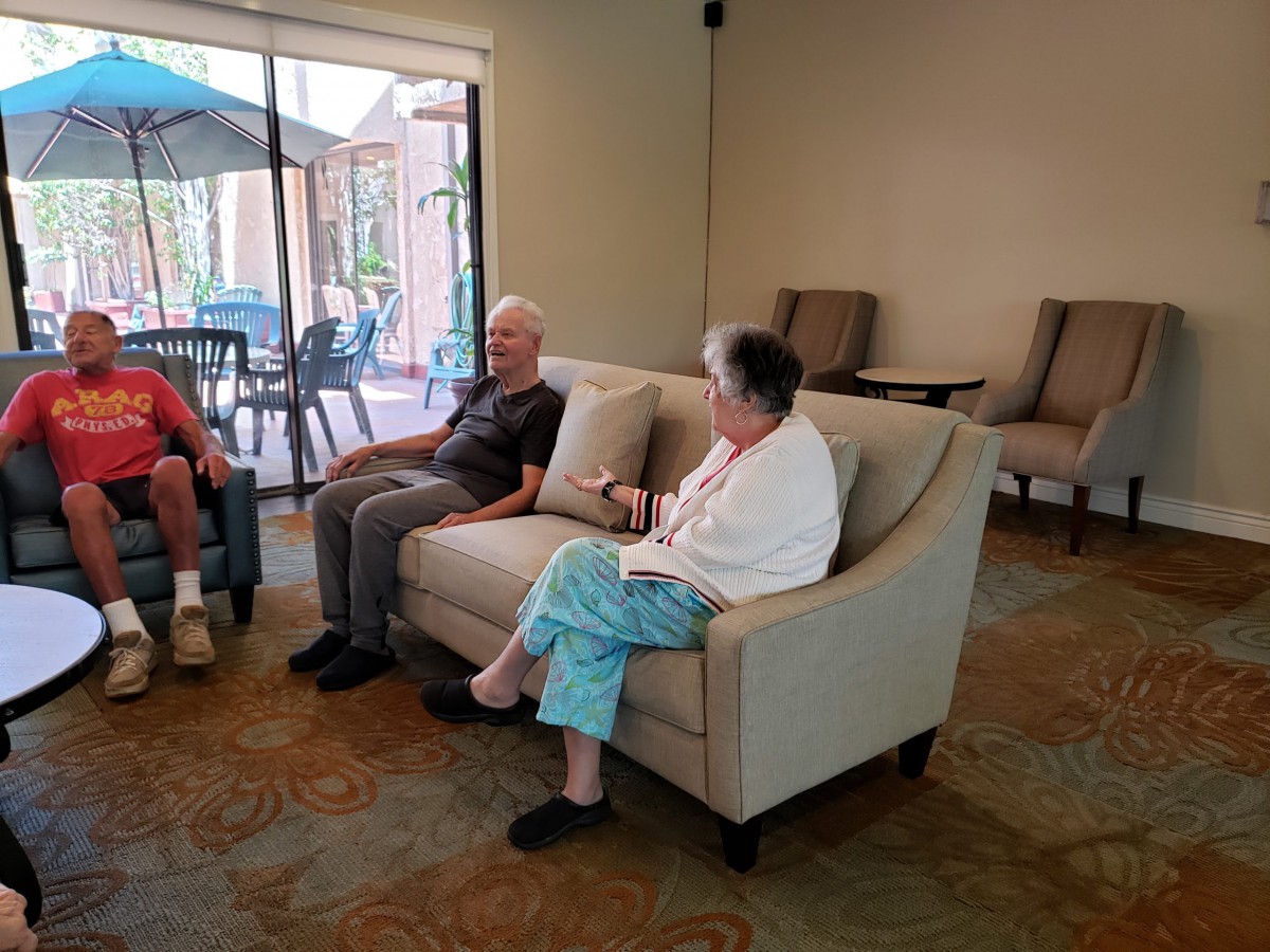 A group of seniors sitting and conversing in a comfortable living room setting.