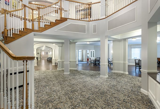 Spacious foyer with an elegant staircase and carpeted flooring.