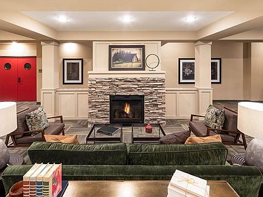 A cozy living room featuring a stone fireplace, comfortable seating, and tasteful artwork.