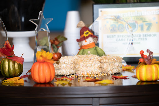 A festive autumn display featuring decorative pumpkins, a scarecrow, and delicious treats.