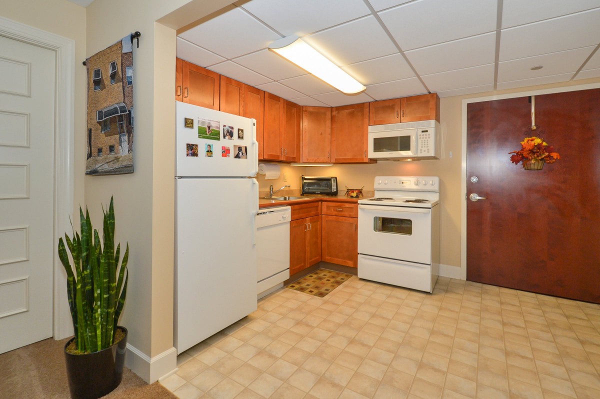 A cozy kitchen with wooden cabinets, featuring a fridge, stove, and microwave.