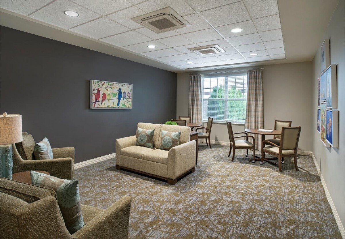 A modern living room with a sofa, chairs, and tables, featuring a large window and stylish decor.