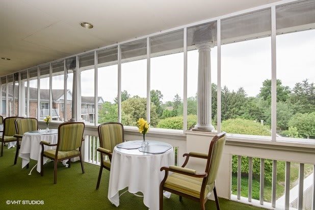 A cozy balcony with a small table and chairs overlooking a lush, green landscape.