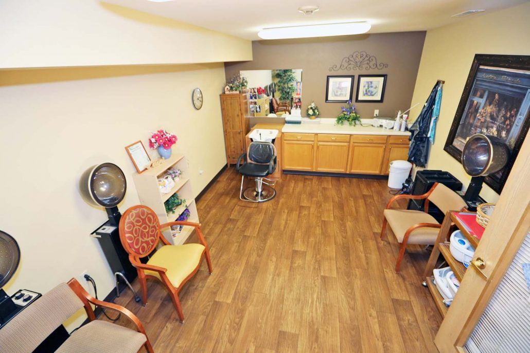 A tidy and well-organized hair salon with wooden floors, chairs, and styling equipment.