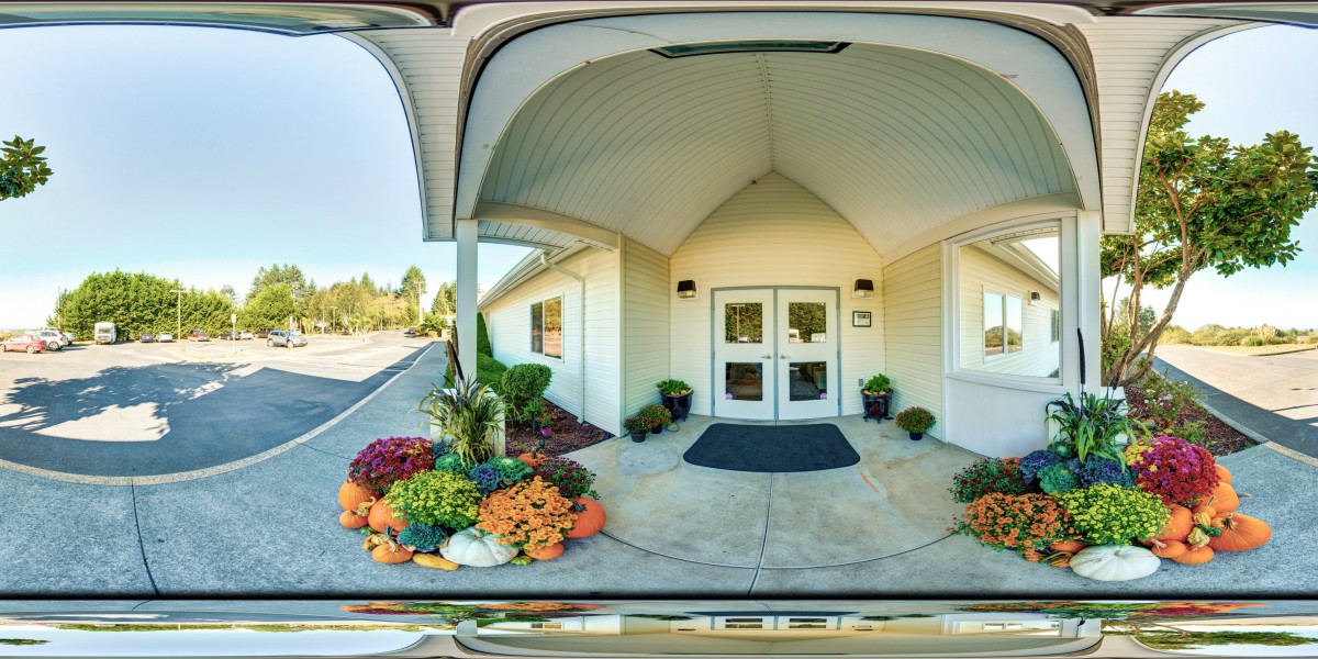 A building entrance featuring decorative plants and flowers.