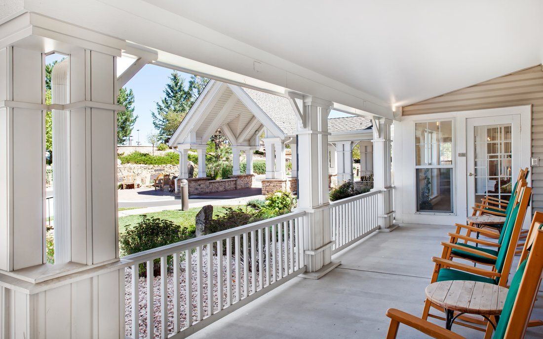 A spacious outdoor porch with seating and a view of a well-maintained garden.
