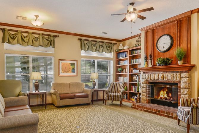 A cozy living room featuring a warm fireplace, comfortable seating, and large windows providing natural light.