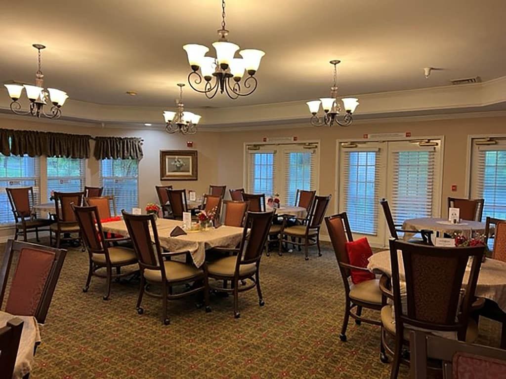 A cozy dining room with multiple tables and chairs arranged under elegant chandeliers.