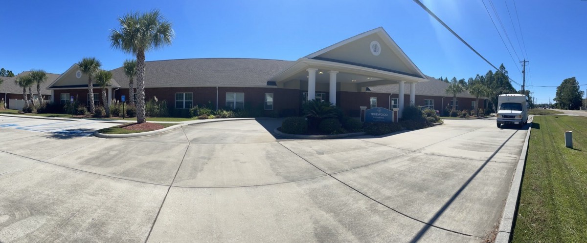 A single-story building with a driveway and clear blue skies.