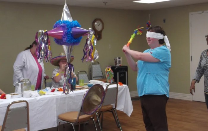 A person wearing a blindfold attempts to hit a piata at a party.