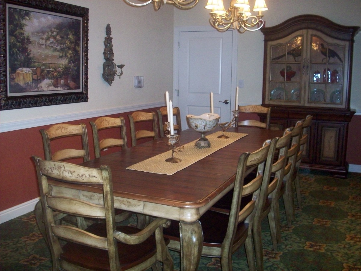 A dining room with a long wooden table and chairs, adorned with candles and a chandelier overhead.