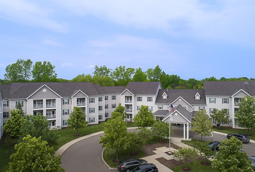 A suburban apartment complex surrounded by lush greenery and a parking lot.