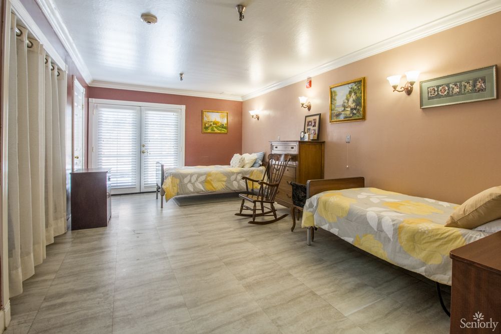 A cozy bedroom featuring two single beds, a rocking chair, and warm decor.