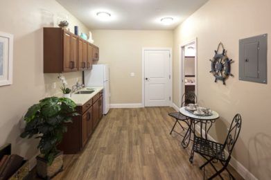 A cozy kitchen with modern cabinets, a small dining set, and wood flooring.