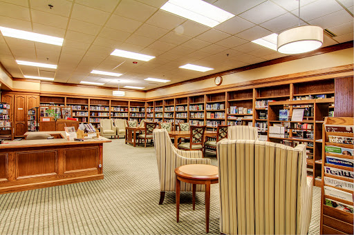 A cozy library setting with shelves full of books and comfortable seating for reading.