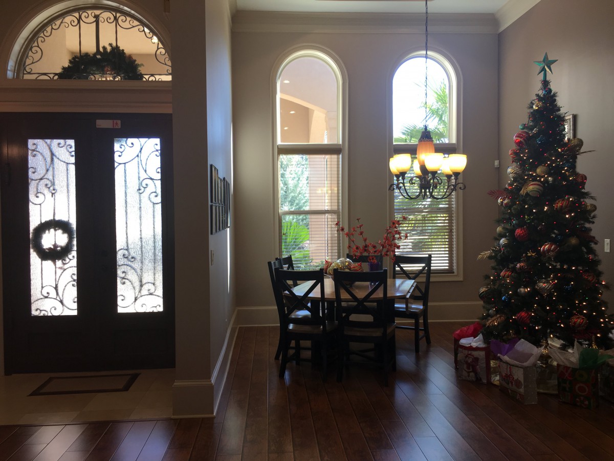 A cozy dining area decorated for the holidays with a Christmas tree and gifts beside a well-lit window.