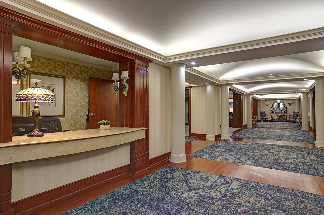 Hotel lobby with a reception desk and carpeted hallway.