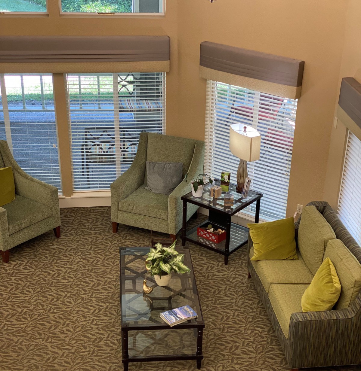 A cozy living room with sofas, chairs, and a coffee table by large windows.
