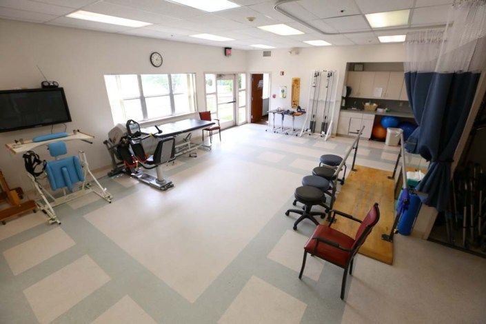 A spacious physical therapy clinic with various exercise equipment and seating areas.