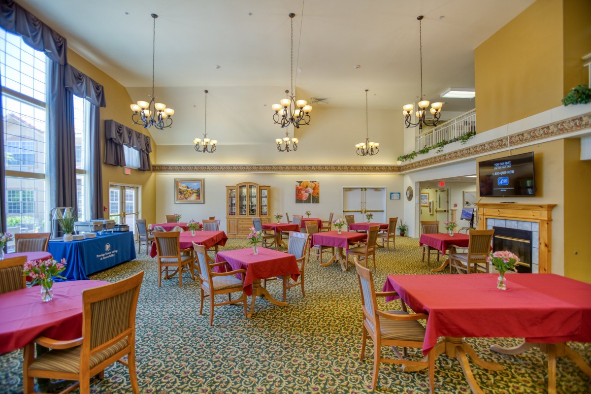 An elegant dining room with multiple tables and chairs, adorned with chandeliers and decorative elements.
