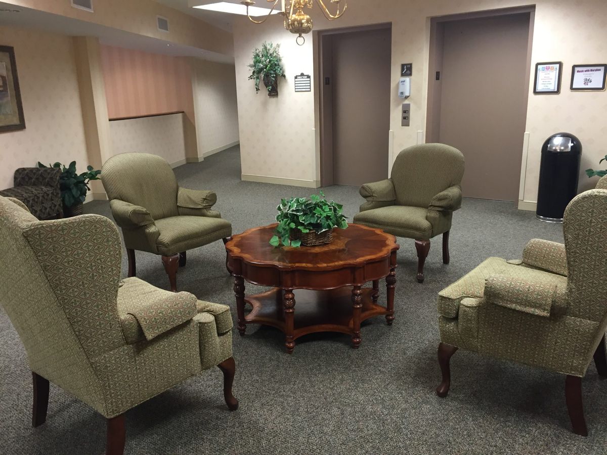 A cozy waiting area with green upholstered chairs and a wooden coffee table.